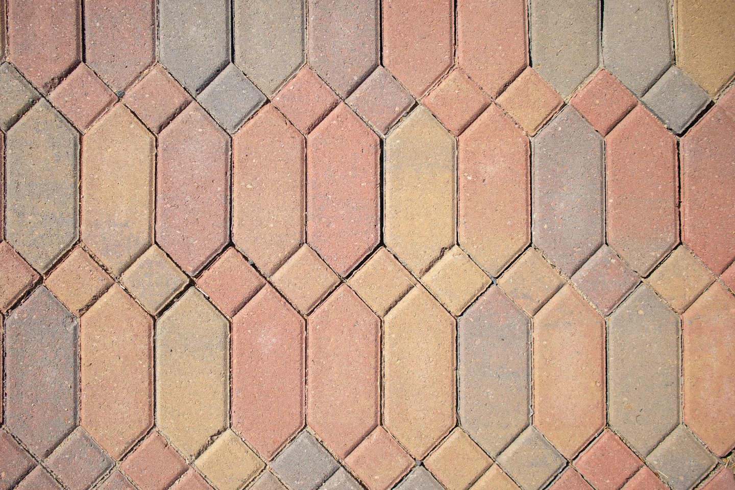 Kamienie brukowe w ziemistych kolorach ułożone w geometryczny wzór.