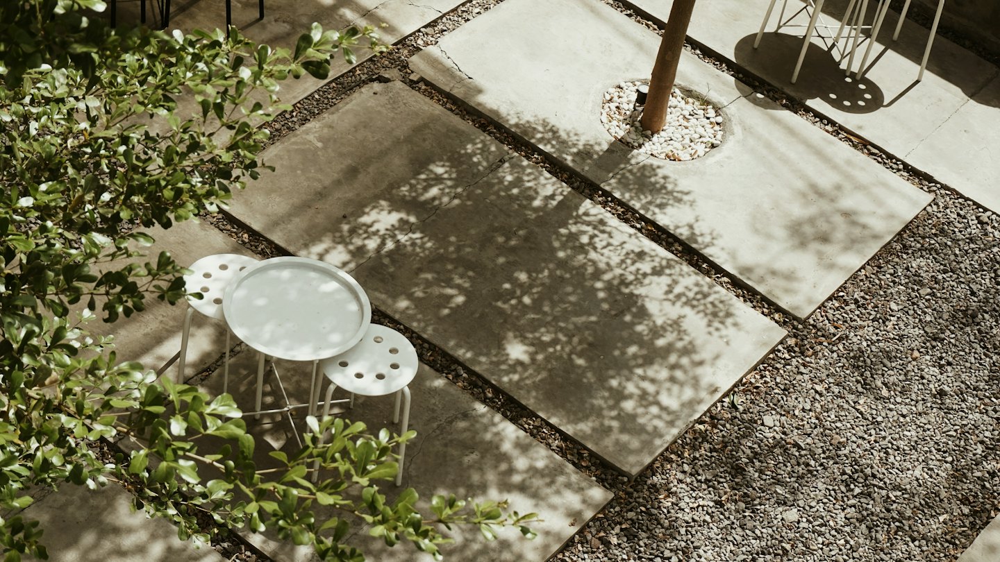 Okrągły biały stolik i stołki stoją na wybrukowanym patio.